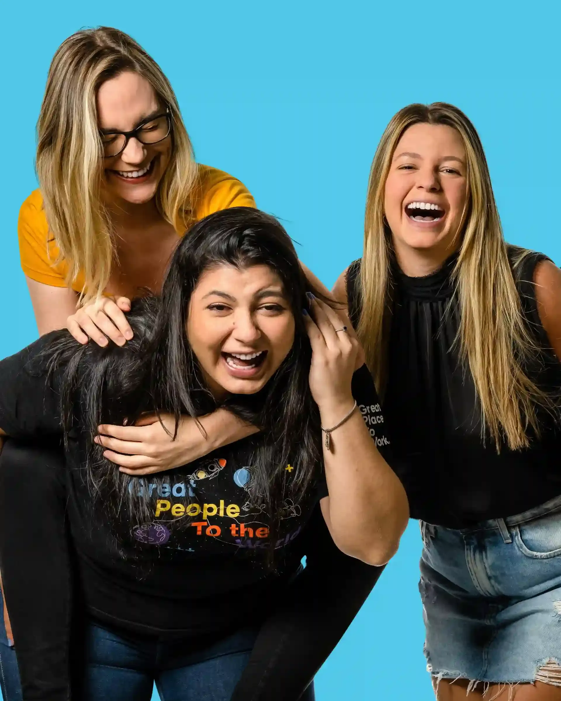 Grupo de quatro mulheres sorrindo e se divertindo juntas contra um fundo azul